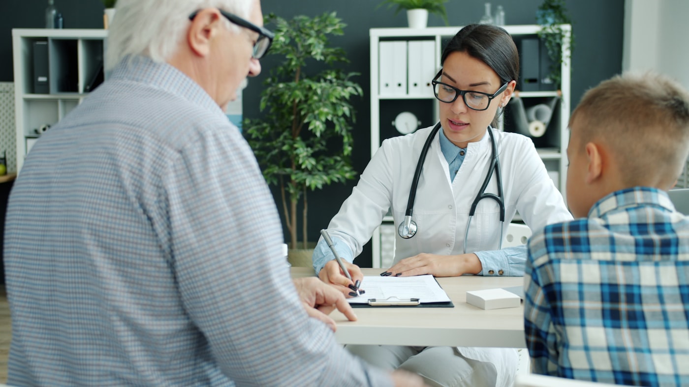 A clinician in conversation with a resident and family member together.