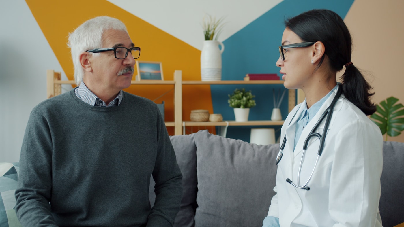 A pharmacist meeting a patient at home to discuss their medications in plain language.