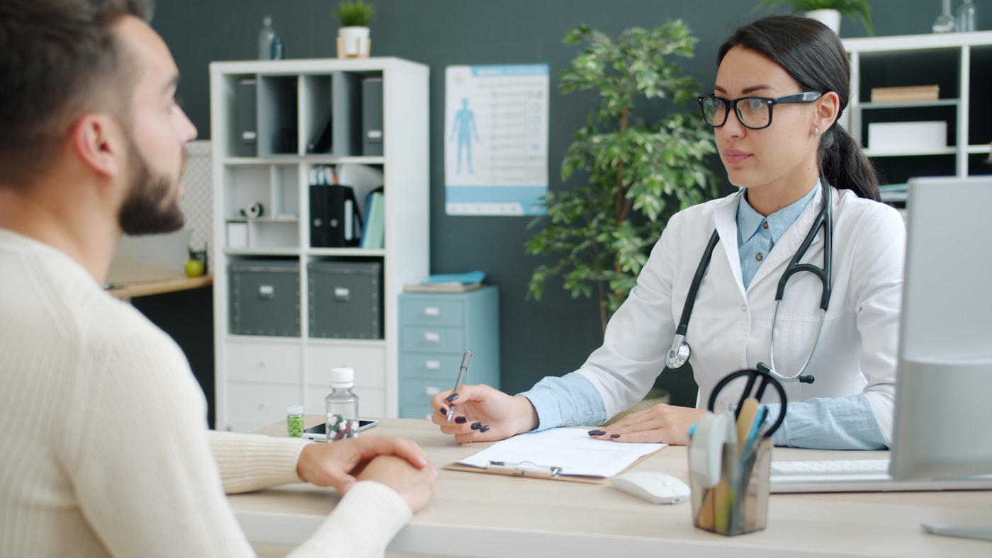 A pharmacist in a thoughtful consultation with a resident in an office.