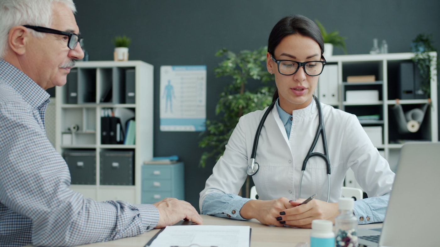 A consultant pharmacist reviewing a patient's medication list together in a calm office setting.