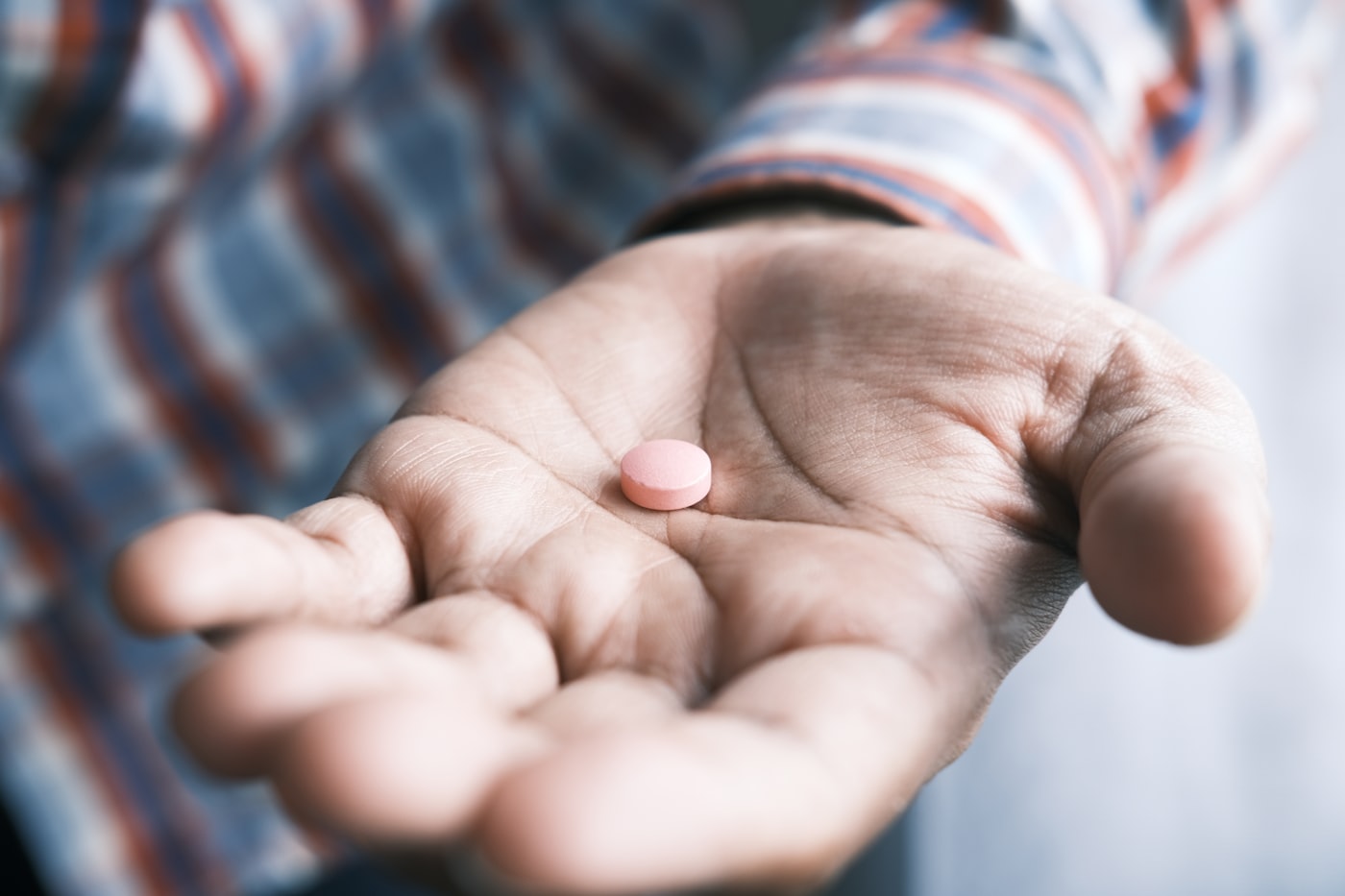 A single pill resting in the palm of an open hand.